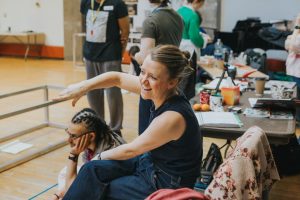 Amy Leach is sitting in a rehearsal room, she is directing, laughing and having fun with her cast and team