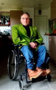 Andrew Miller has short borwn hari, is wearing a bright grass green jacket and a black polo next junper. 