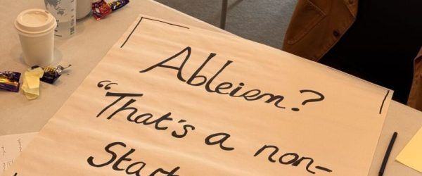 Photo of a large flip chart sheet lying on a table with lots of pens and mugs and stationary around it. The flip chart page as Ableism? Thats a non starter written on it